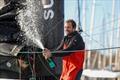 Vulnerable skipper Sam Goodchild (GBR) is celebrating with champagne after taking 9th place in the Vendée Globe